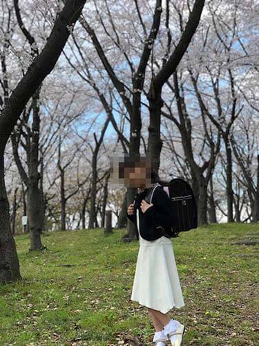 桜並木の中で牛革ボルサパステルクラシックを背負う女の子（全身・背面ショット）