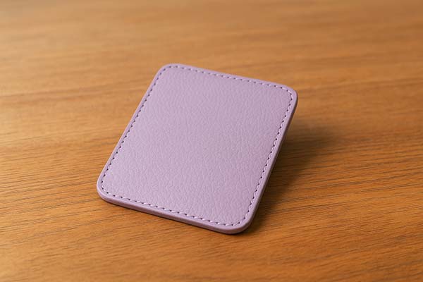 紫のランドセル革サンプルを机の上に置いた写真。落ち着いたラベンダー系の色味と上品なツヤ感が伝わる。